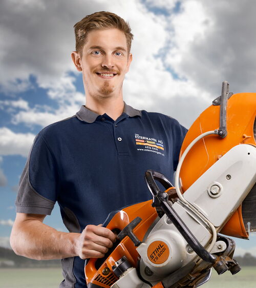Handwerker mit blauem T-Shirt und Trennsäge vor Wolkenhintergrund