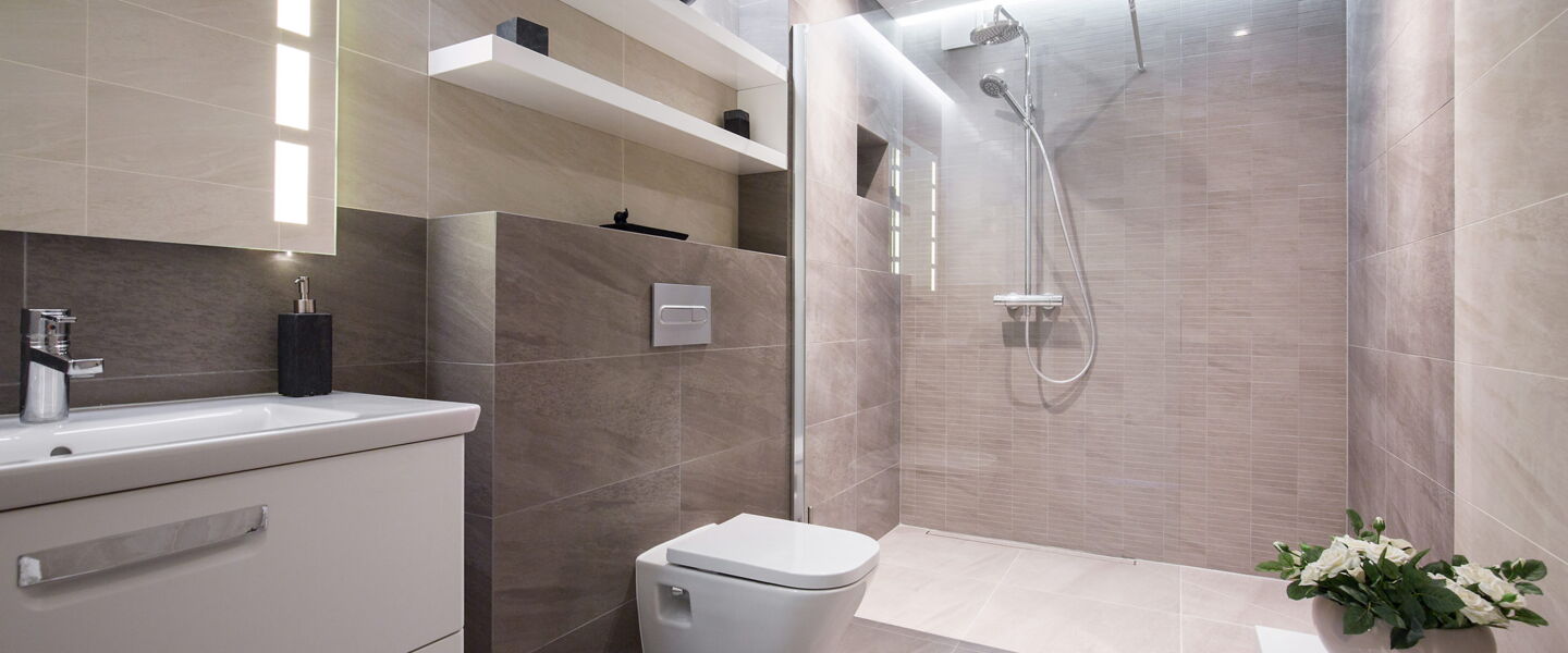 Modernes Bad mit braunen Fliesen mit Waschtisch, Toilette und rollstuhlgängiger Dusche