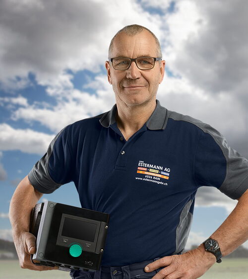 Jost Fellmann Handwerker mit blauem Shirt und Elektrogerät vor Wiese und Wolkenhimmel