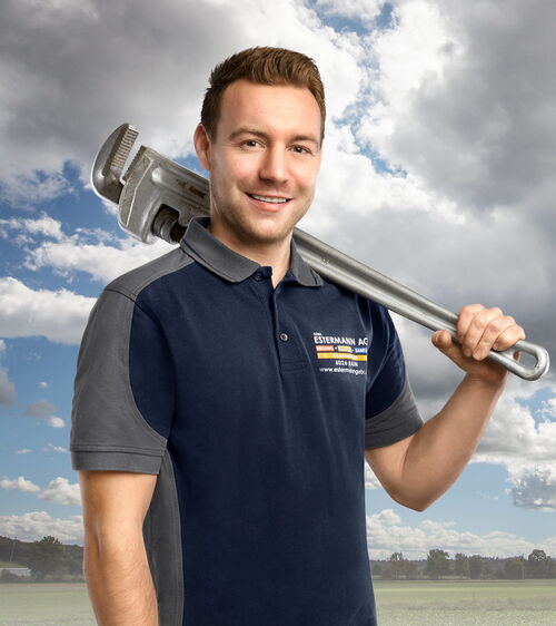 Reto Burkart Handwerker mit blauem Shirt und grosser Rohrzange vor Wiese und Wolkenhimmel